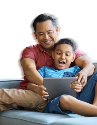 Man and boy sitting on a sofa playing with a tablet 